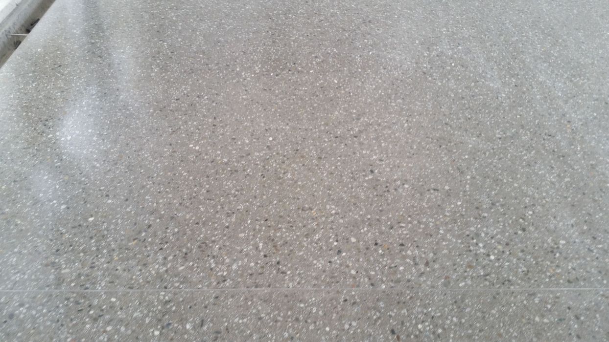 Eine Nahaufnahme eines grauen Terrazzo-Bodens mit feiner Körnung und glatter, polierter Textur.