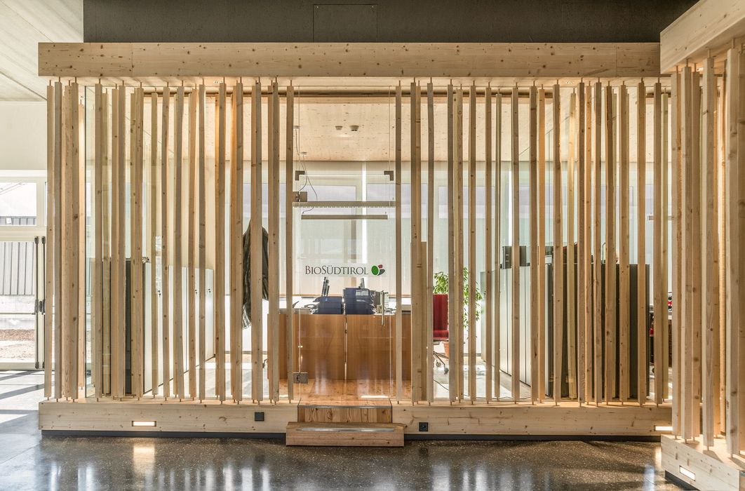 Büro von Bio Südtirol mit einer Trennwand aus vertikalen Holzlamellen und einer zentralen Glastür, die den Blick ins Innere freigibt.