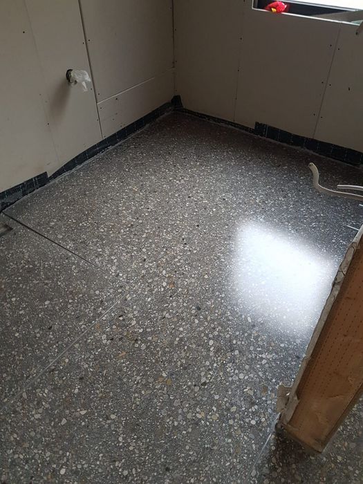 Blick auf einen frisch verlegten Terrazzoboden in einem Raum mit Gipskartonwänden im Rohbau.