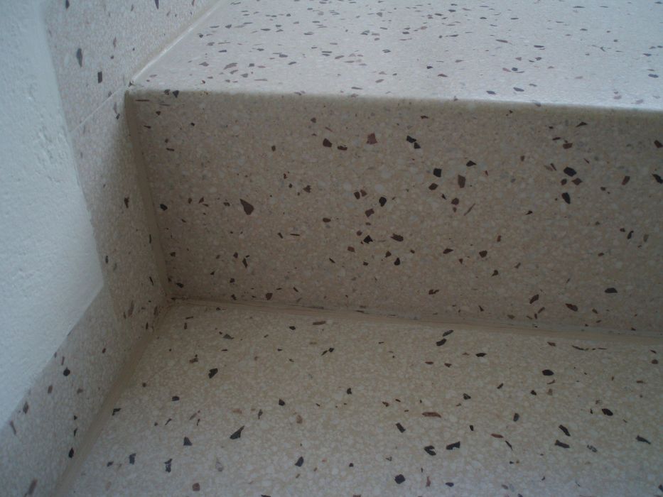 Nahaufnahme einer Treppenstufe aus beigem Terrazzo mit gesprenkelter Textur.