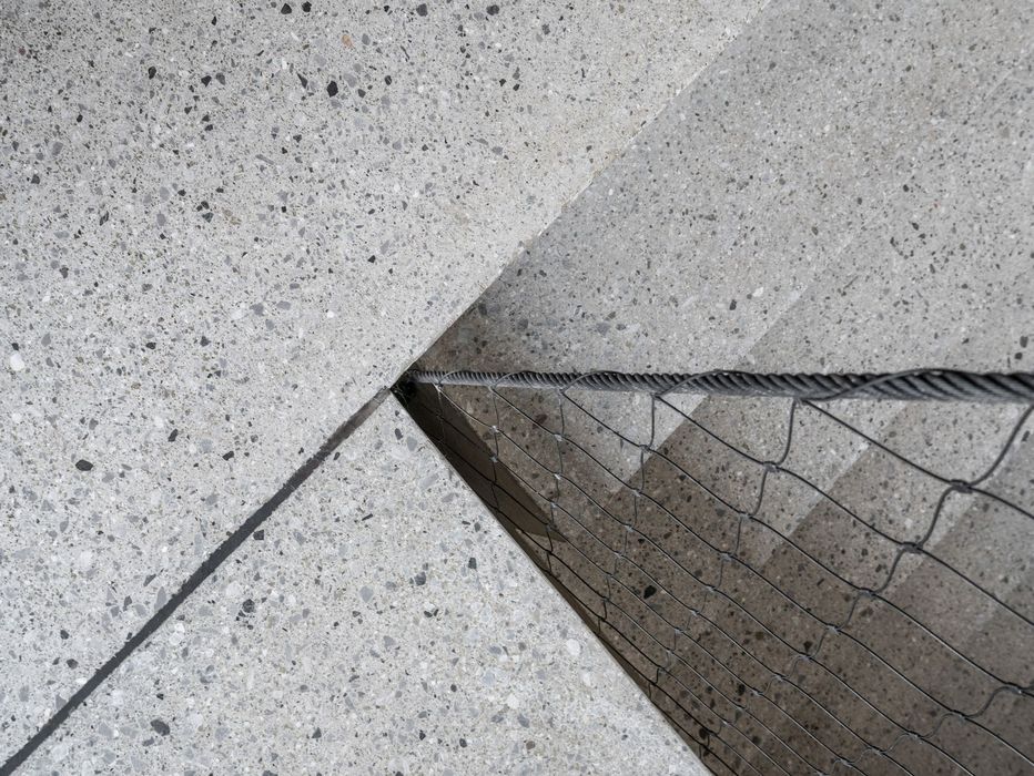 Eine Nahaufnahme einer Treppenkante aus Granit mit einem Schutznetz im Vordergrund, fotografiert von oben im steilen Winkel.