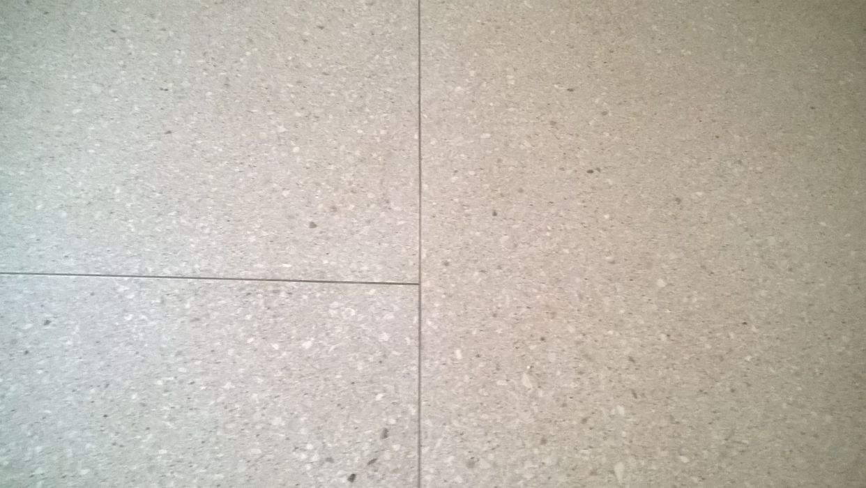 Eine Nahaufnahme von hellgrauen Bodenfliesen in Terrazzo-Optik mit feinen Fugen.