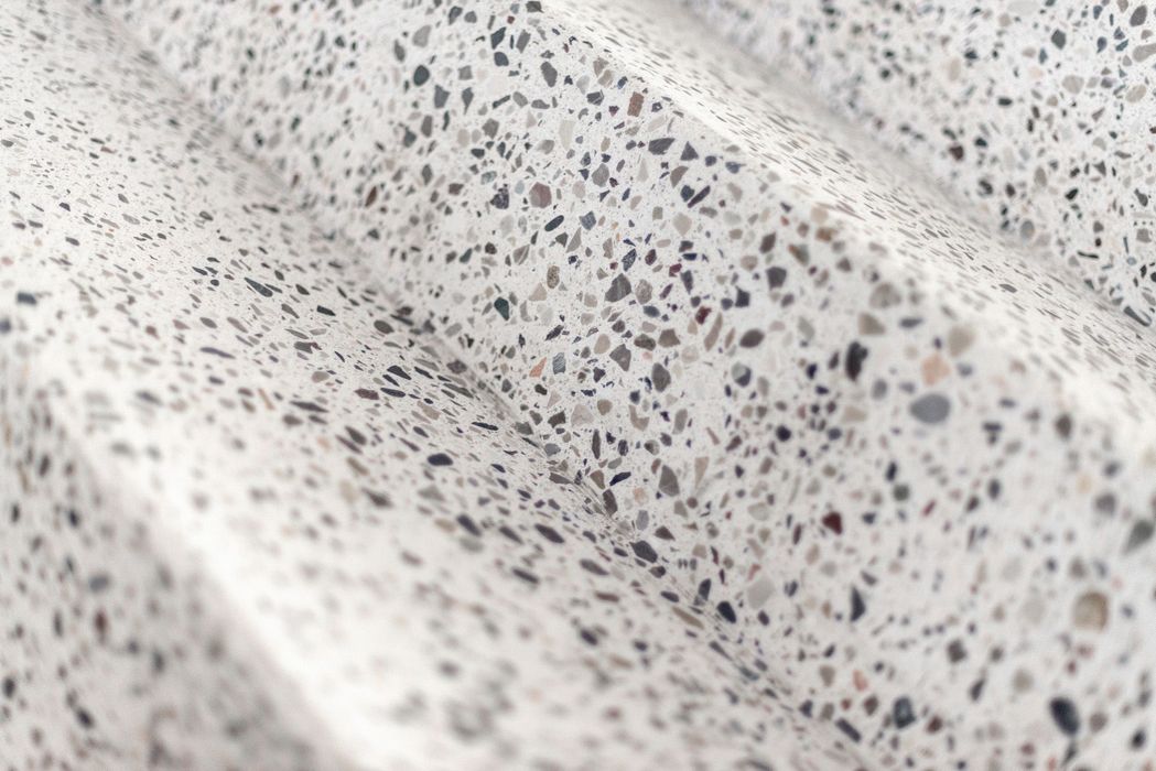 Eine Nahaufnahme einer Treppe aus hellem Terrazzo mit gesprenkelter Oberfläche.