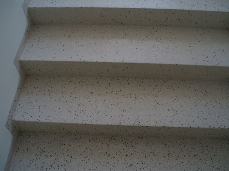 Nahaufnahme einer Treppe aus hellem Material mit gesprenkelter, steinartiger Textur.