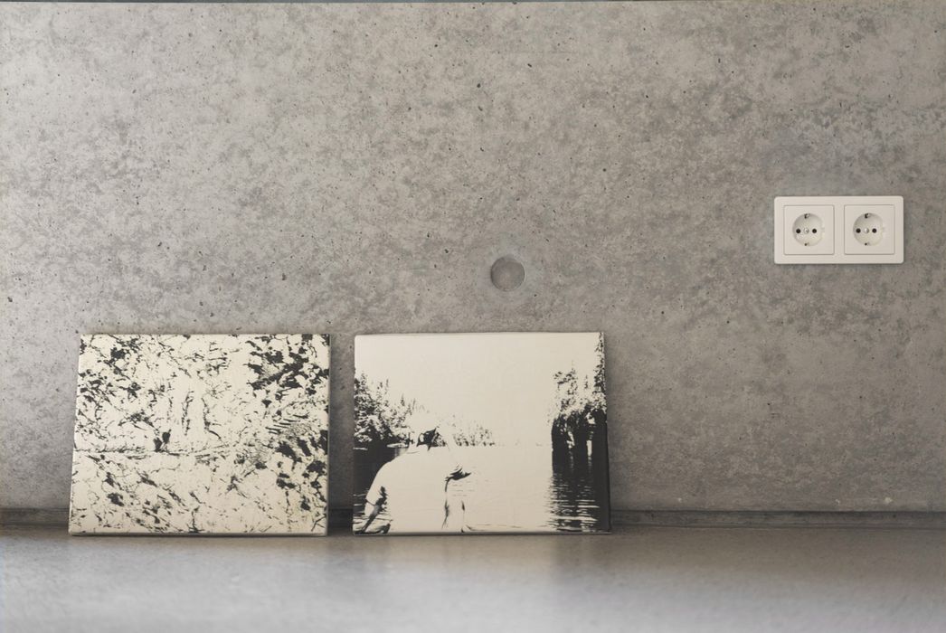 Zwei schwarz-weiße Bilder stehen auf einer Arbeitsplatte vor einer Betonwand mit einer Steckdose.